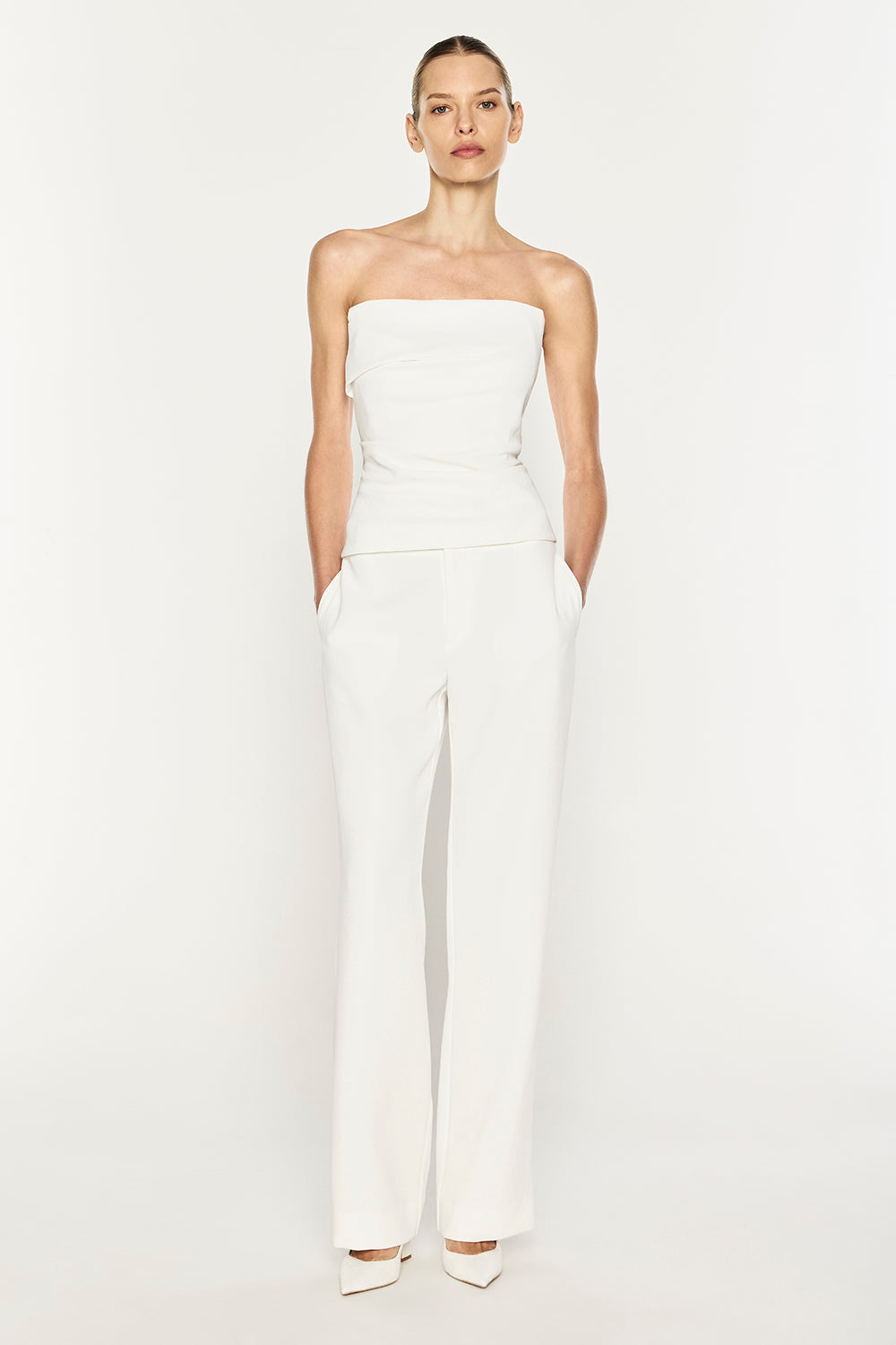 A model wearing a white strapless tube top and matching wide-leg trousers, standing against a plain white studio background.