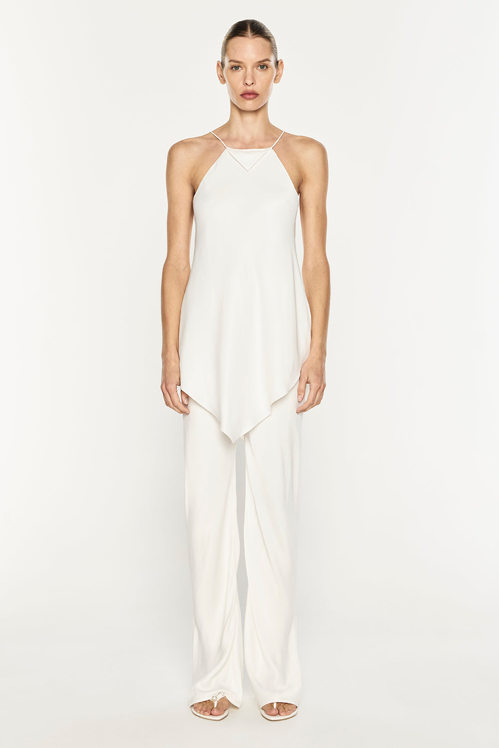 A model wearing a white sleeveless camisole top with thin straps and matching wide-leg trousers, photographed against a plain white studio background.