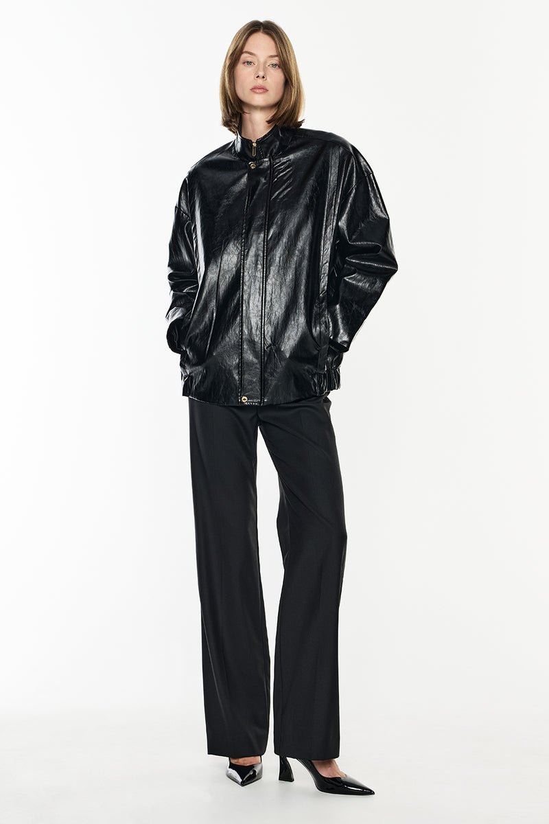 Person wearing a shiny black jacket and pants on a white background